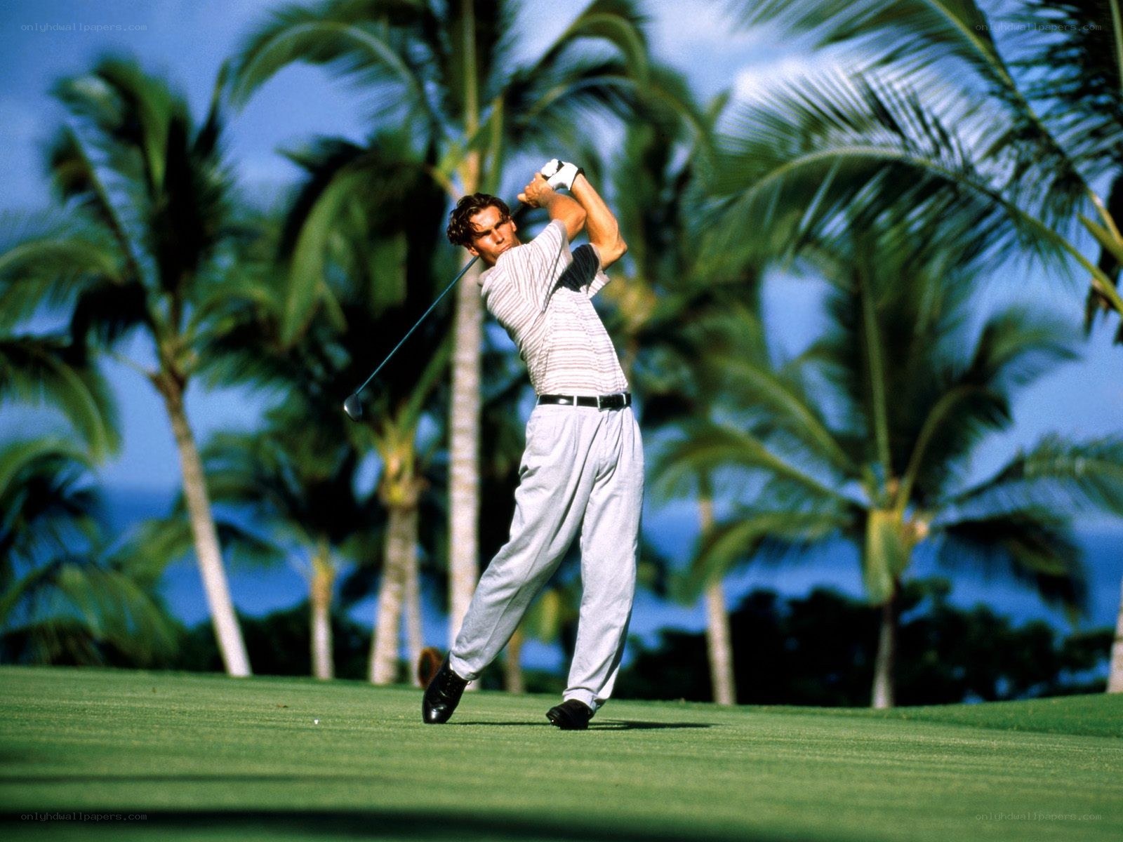 Golfer swinging on tropical course