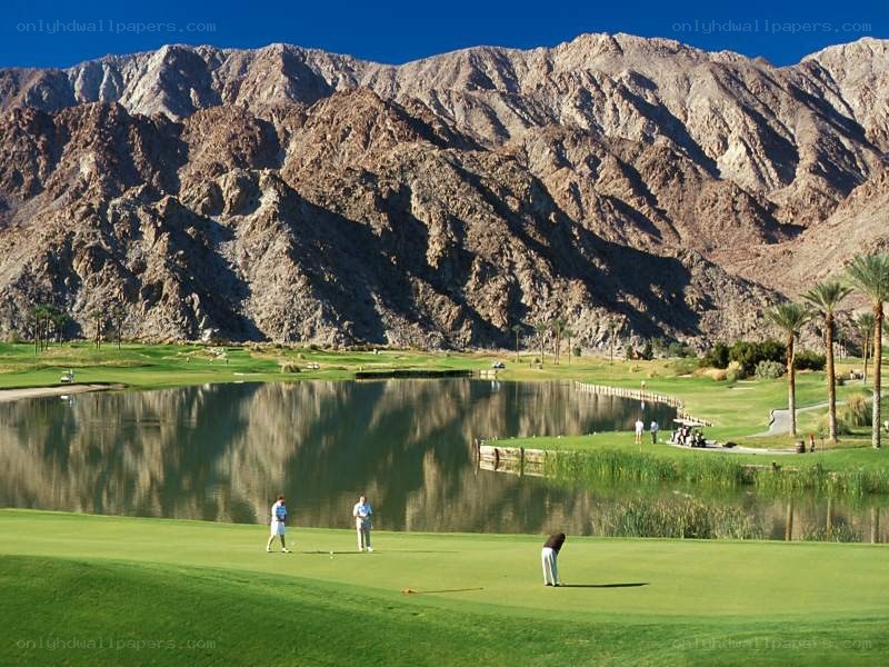 Golfers on a course with mountains