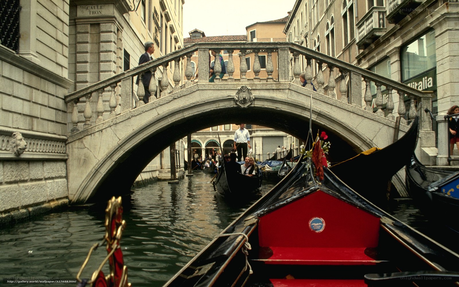 Gondolas under a stone bridge in Venice