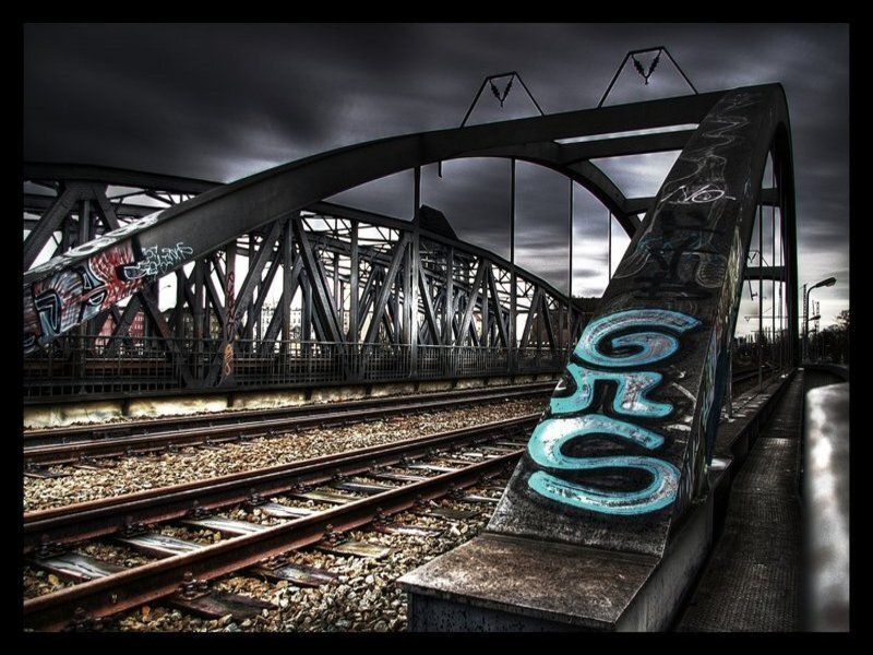 Graffiti-covered bridge under stormy sky