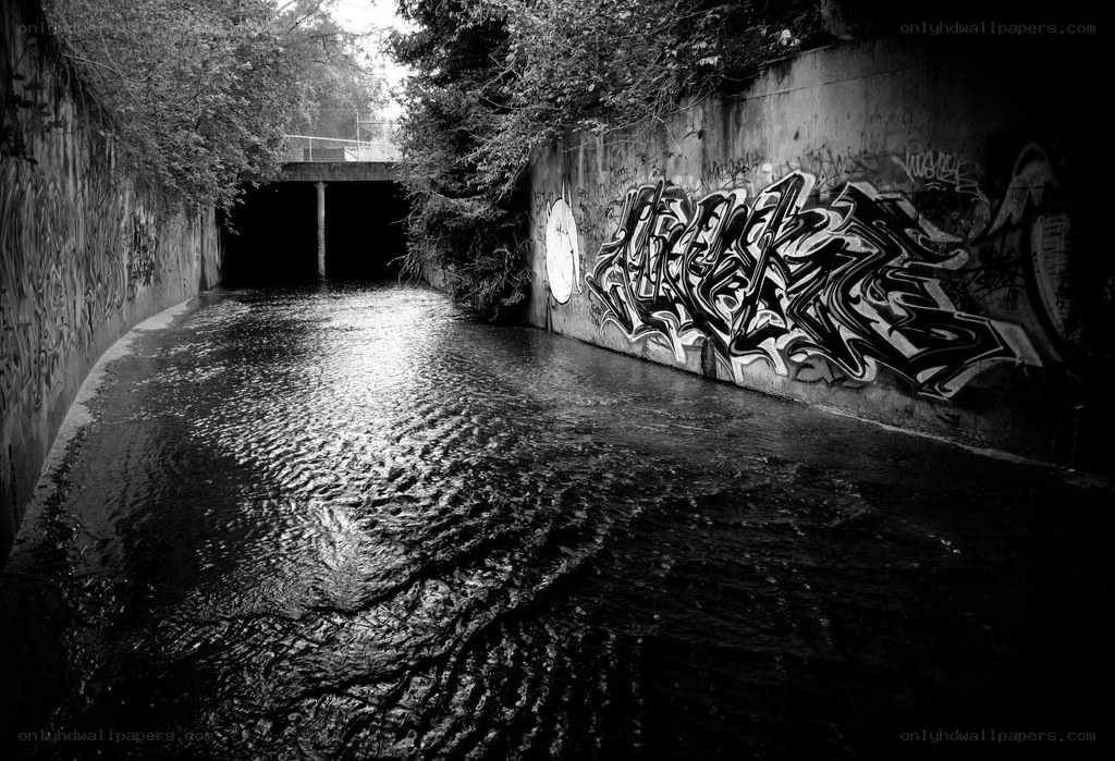 Graffiti-covered canal under bridge