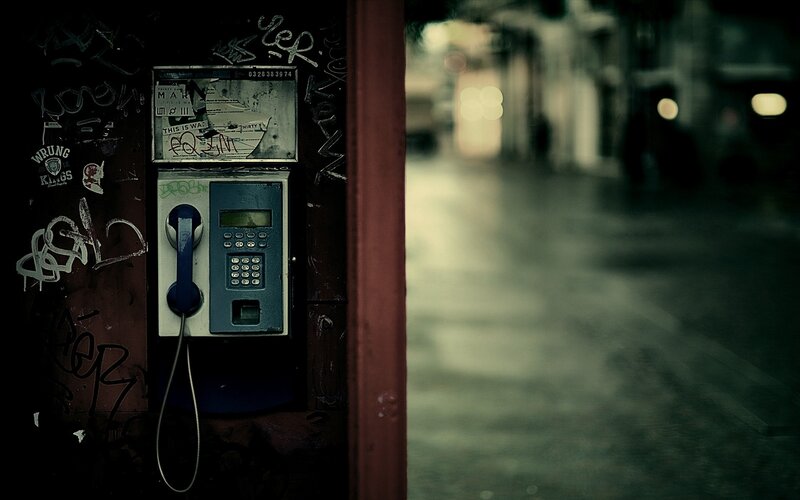 graffiti-covered payphone on a dark street
