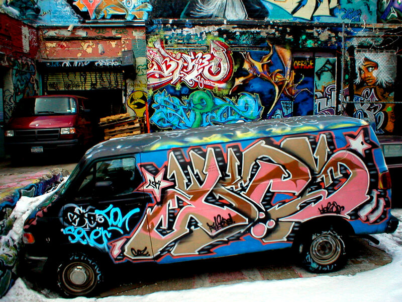 Graffiti-covered van in alley