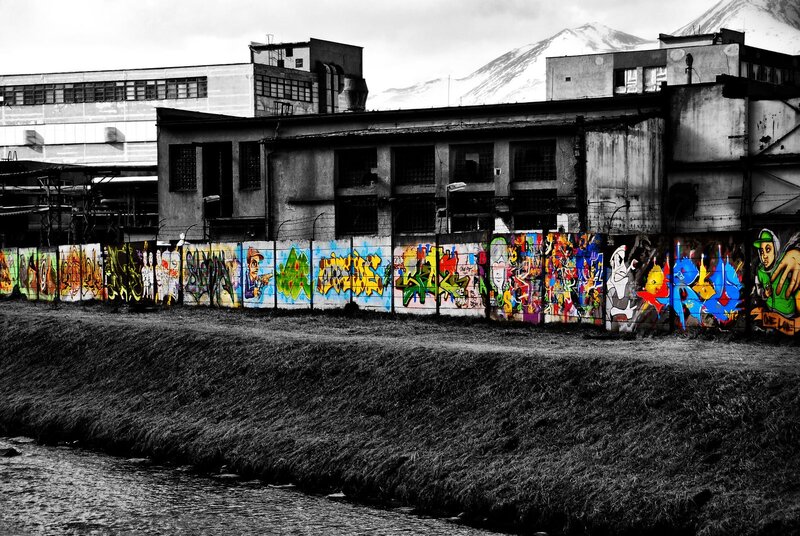 Graffiti-covered wall near industrial buildings