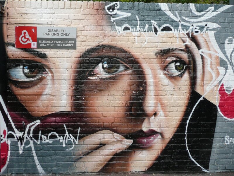 graffiti of woman's face on brick wall