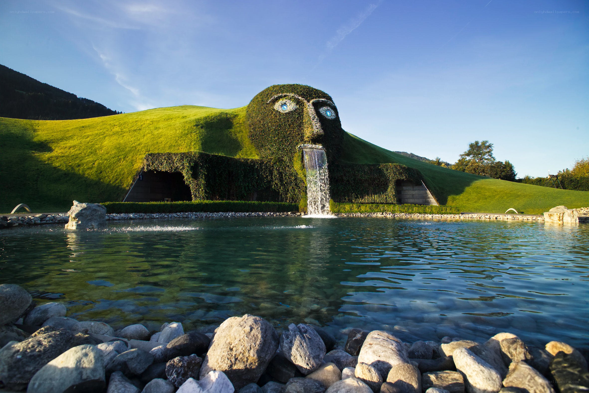 Grass-covered face sculpture with waterfall