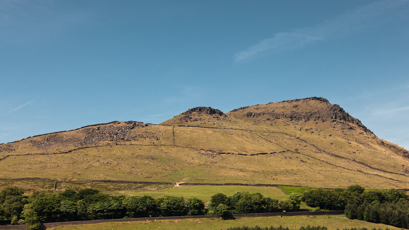 Grass-covered hill under blue sky