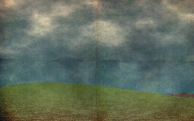 Grass field under cloudy sky