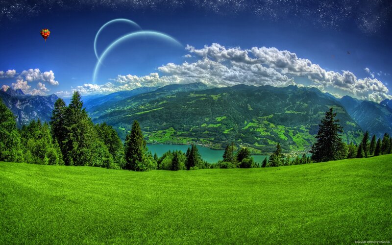 Grass field with mountains and hot air balloon