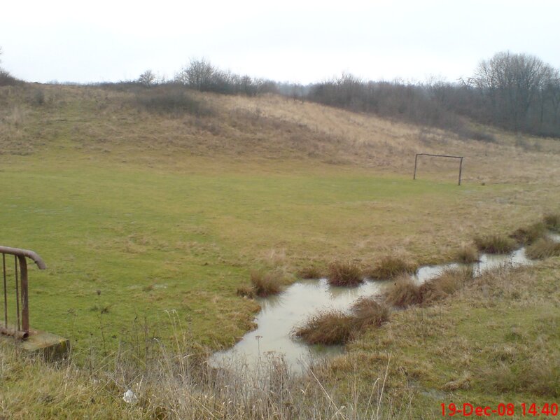 Grassy field with stream and goalpost