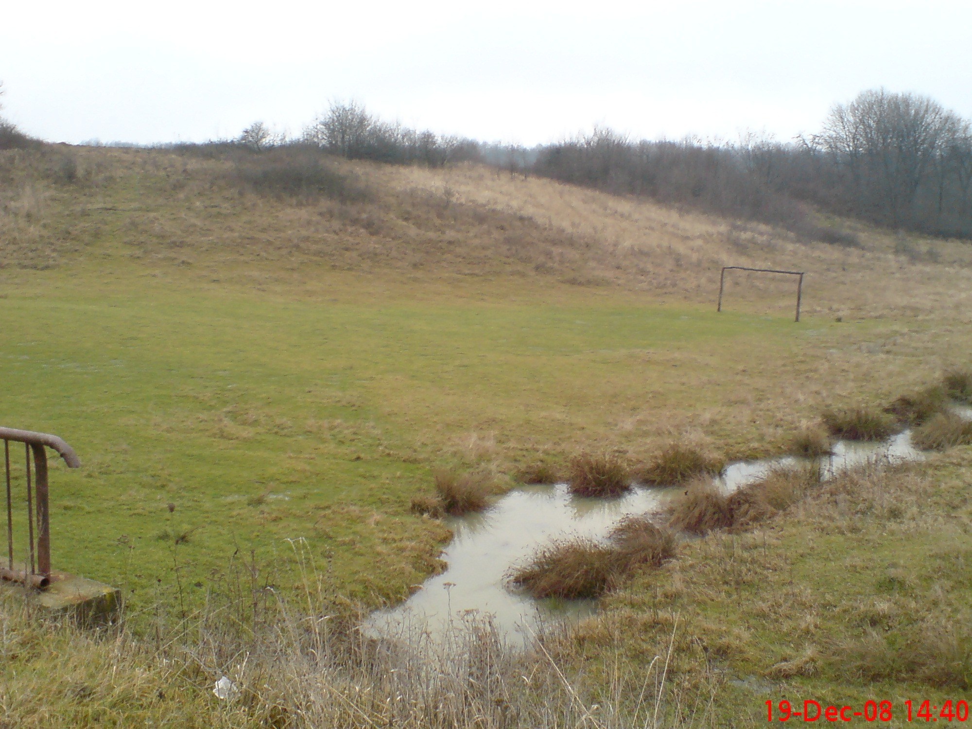 Grassy field with stream and goalpost