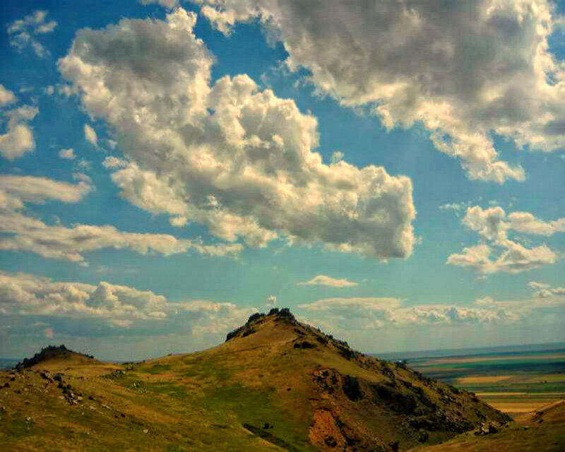 Grassy hill under cloudy sky