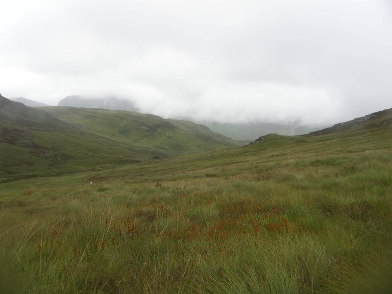 Grassy hills under cloudy sky