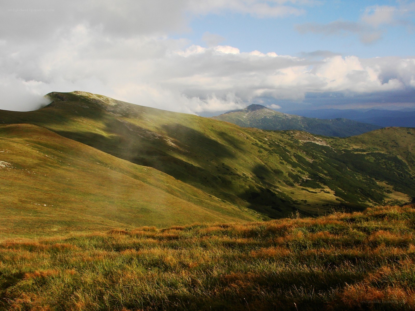 Grassy mountain slopes under cloudy sky