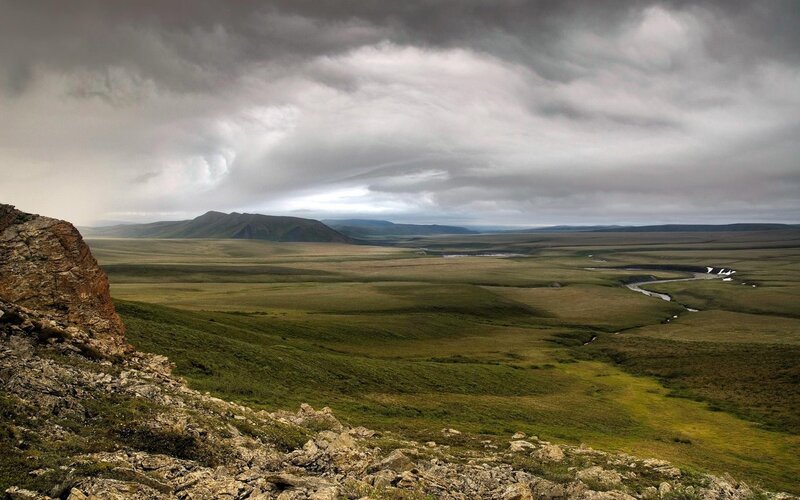 Grassy tundra under stormy sky