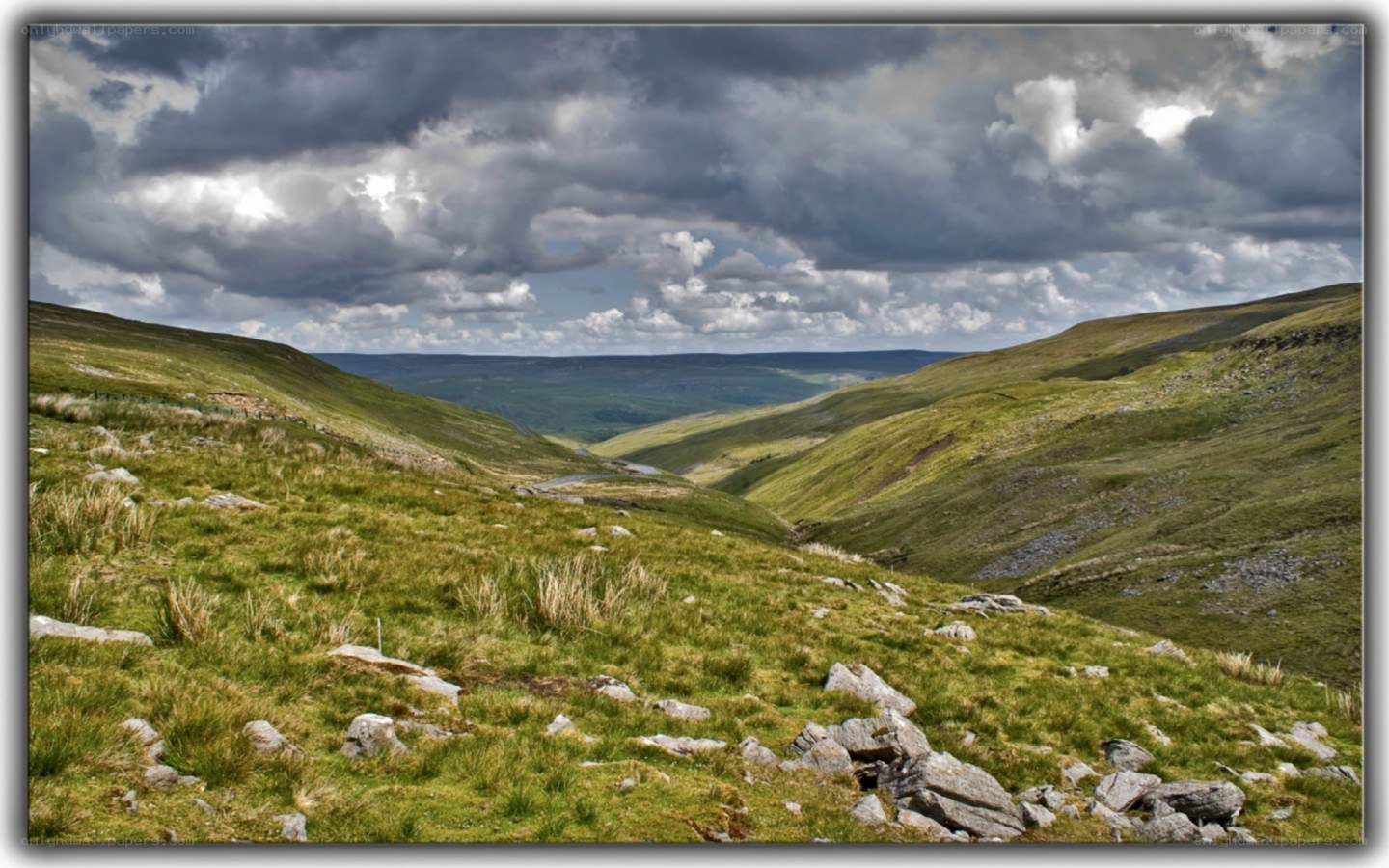 Grassy valley under cloudy sky
