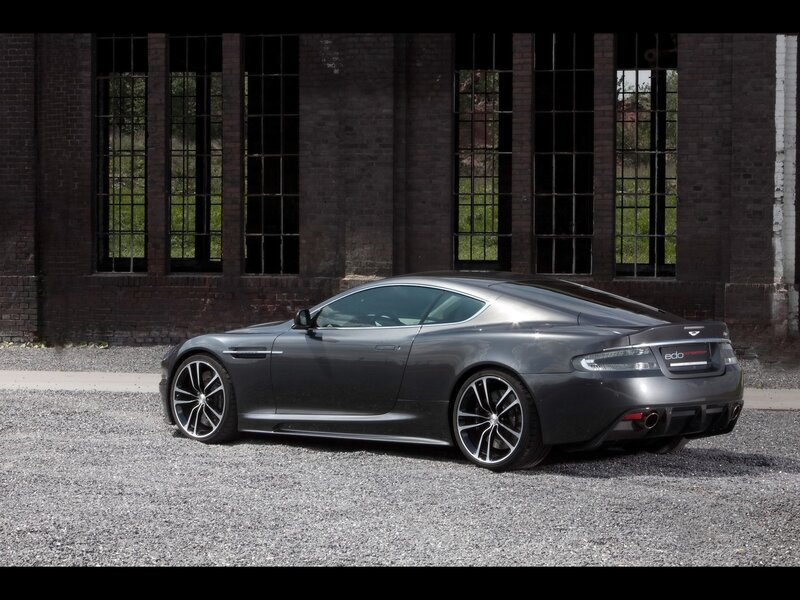 Gray Aston Martin in front of brick building