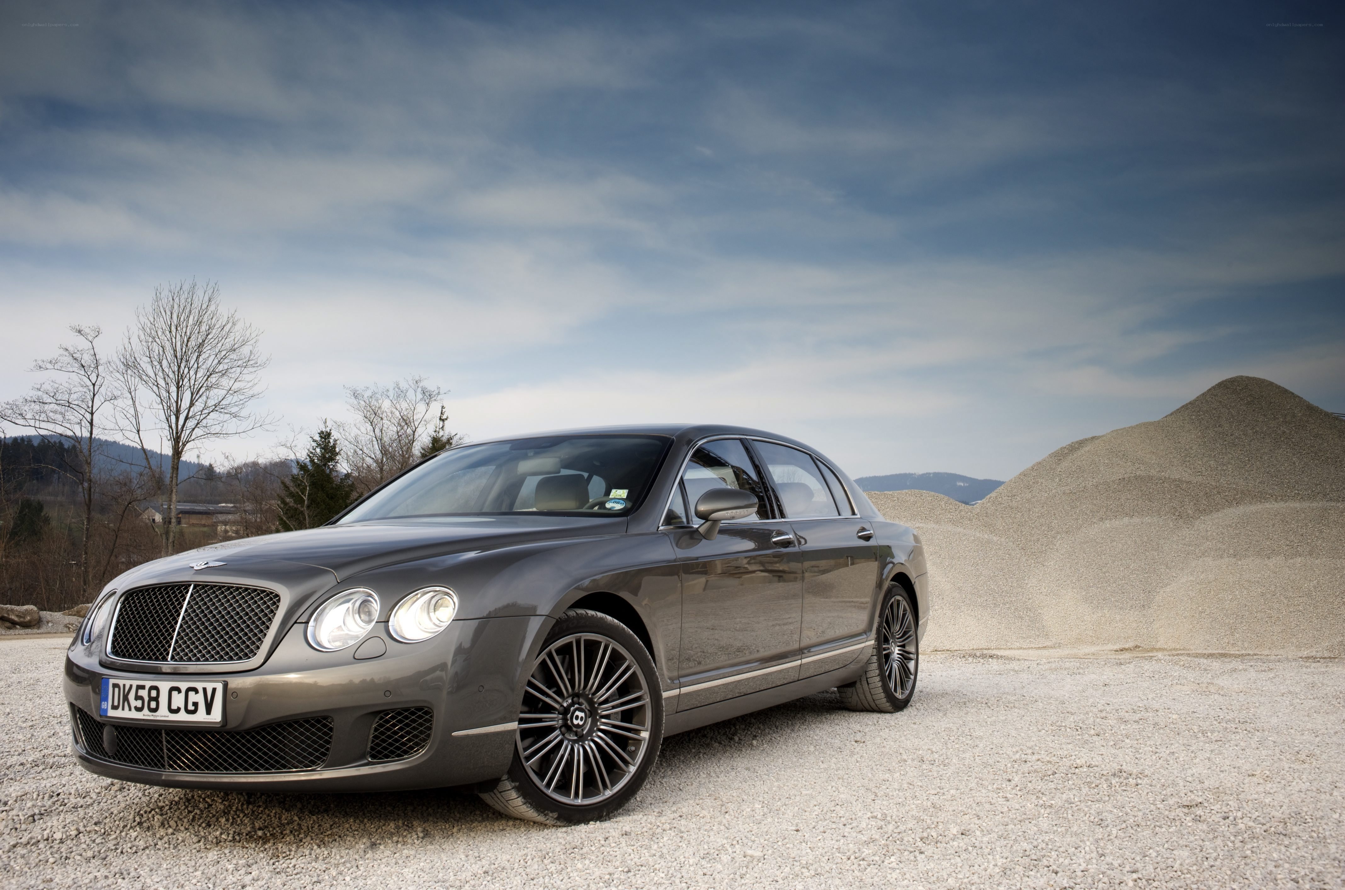Gray Bentley parked on gravel