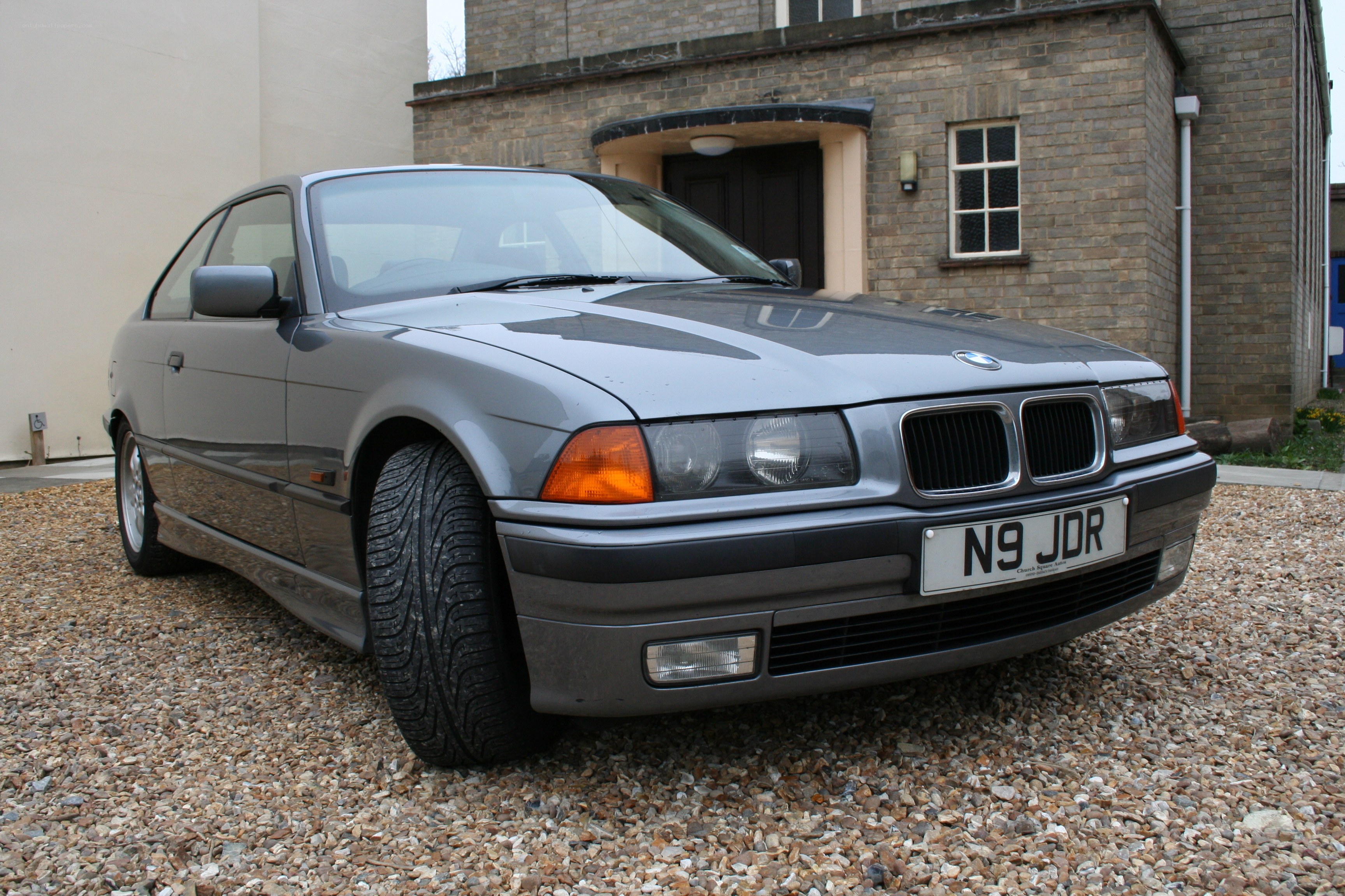 Gray BMW parked on gravel