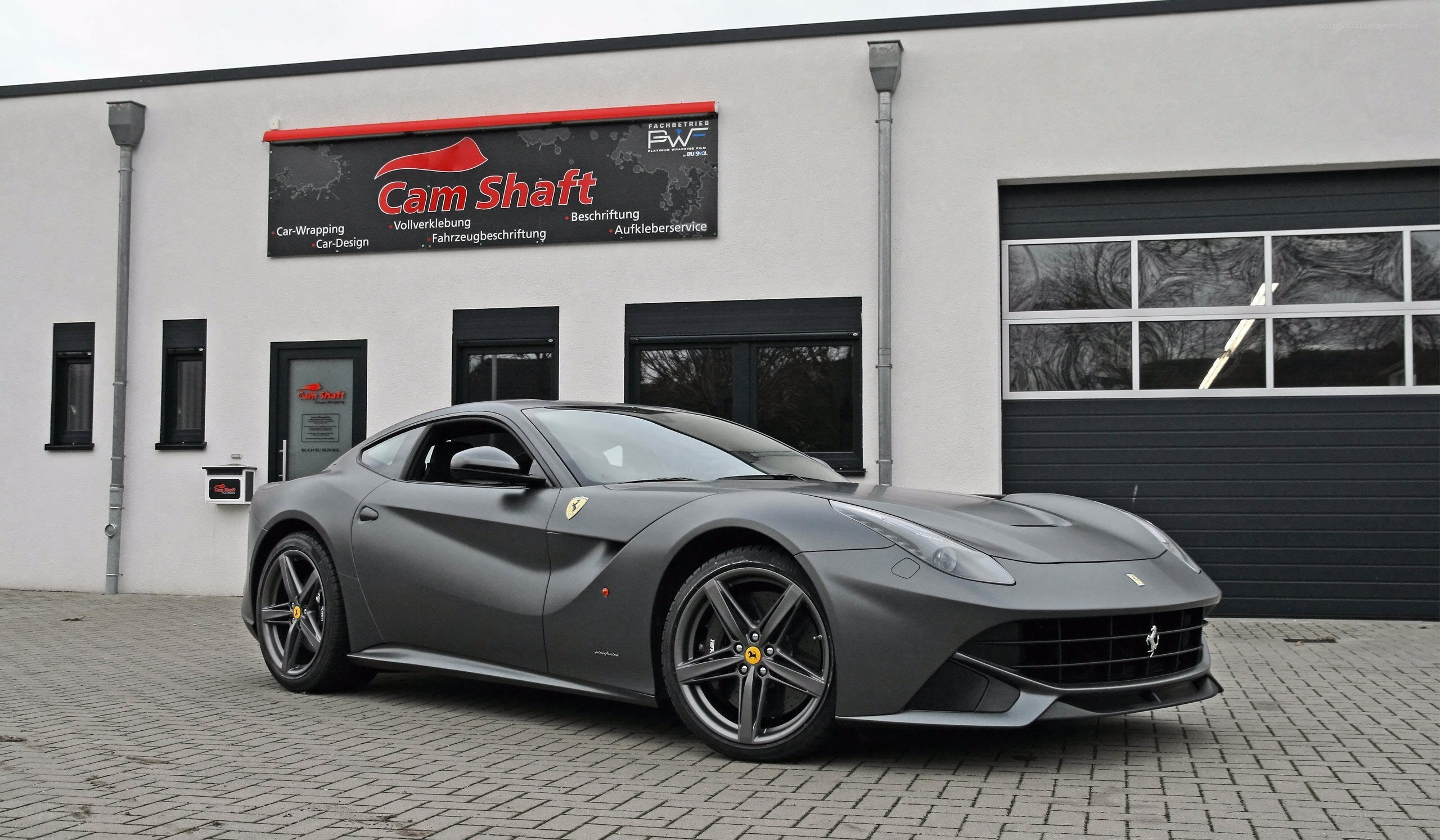 Gray Ferrari F12 parked outside shop