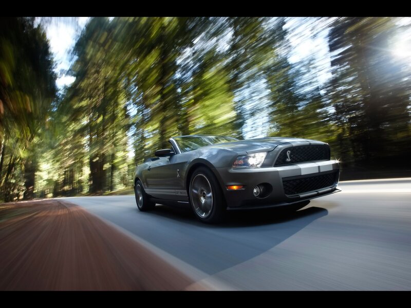 Gray Ford Mustang convertible on forest road