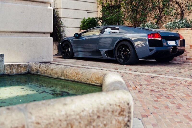 Gray Lamborghini parked by fountain