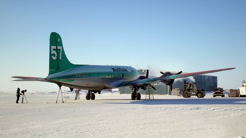 Green airplane on snowy tarmac