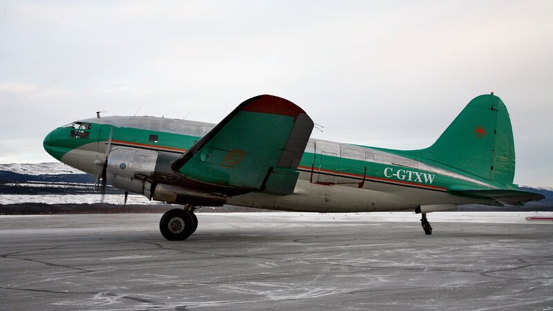 Green and silver airplane on tarmac