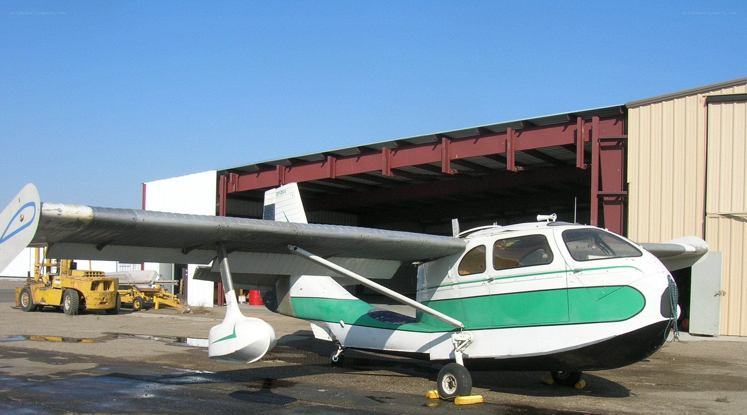 green and white seaplane at hangar