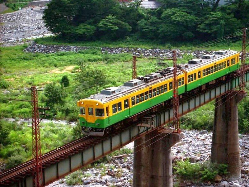 Green and yellow train on a bridge