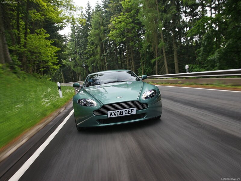 green aston martin on forest road