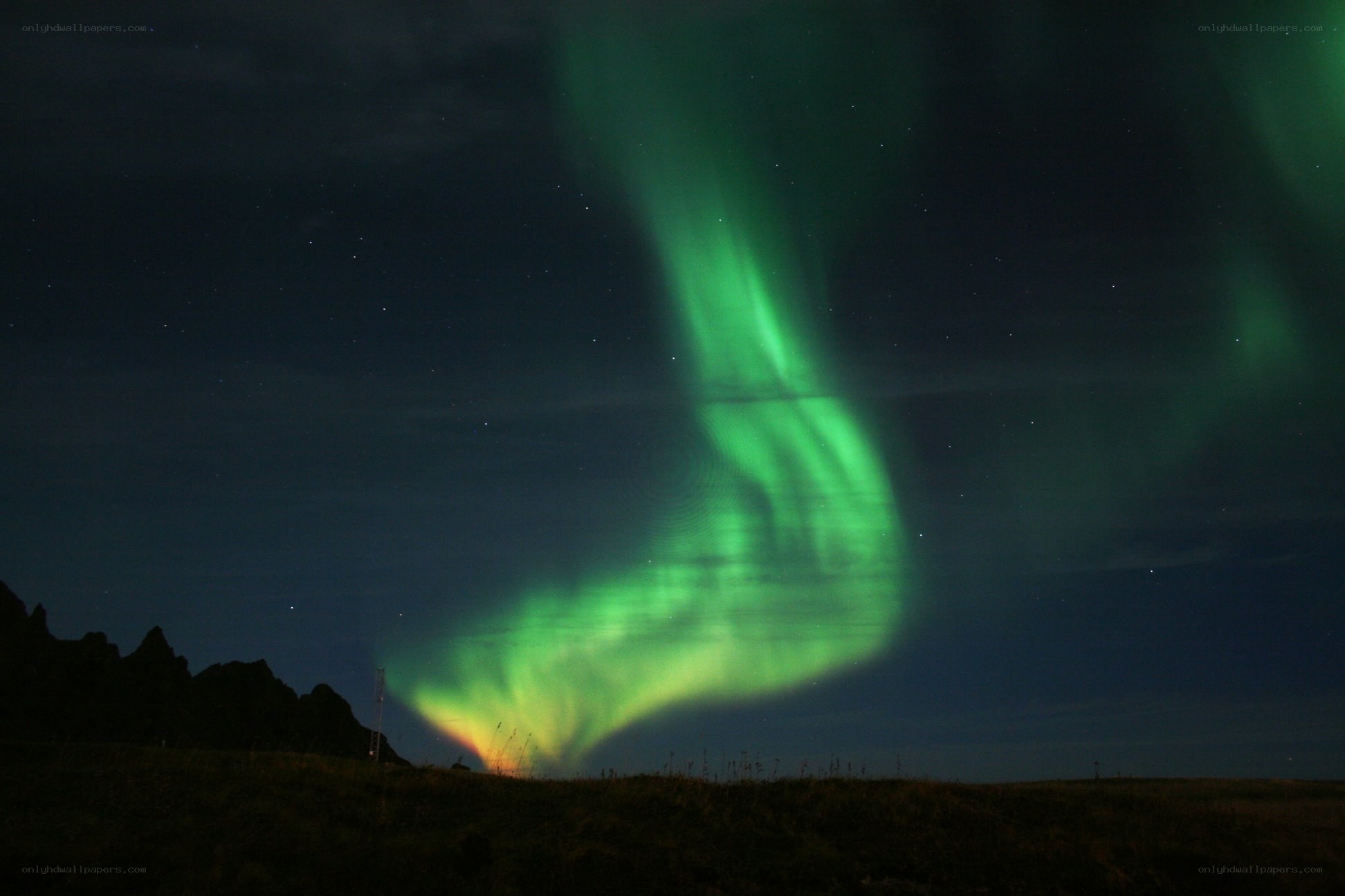 Green aurora over dark landscape