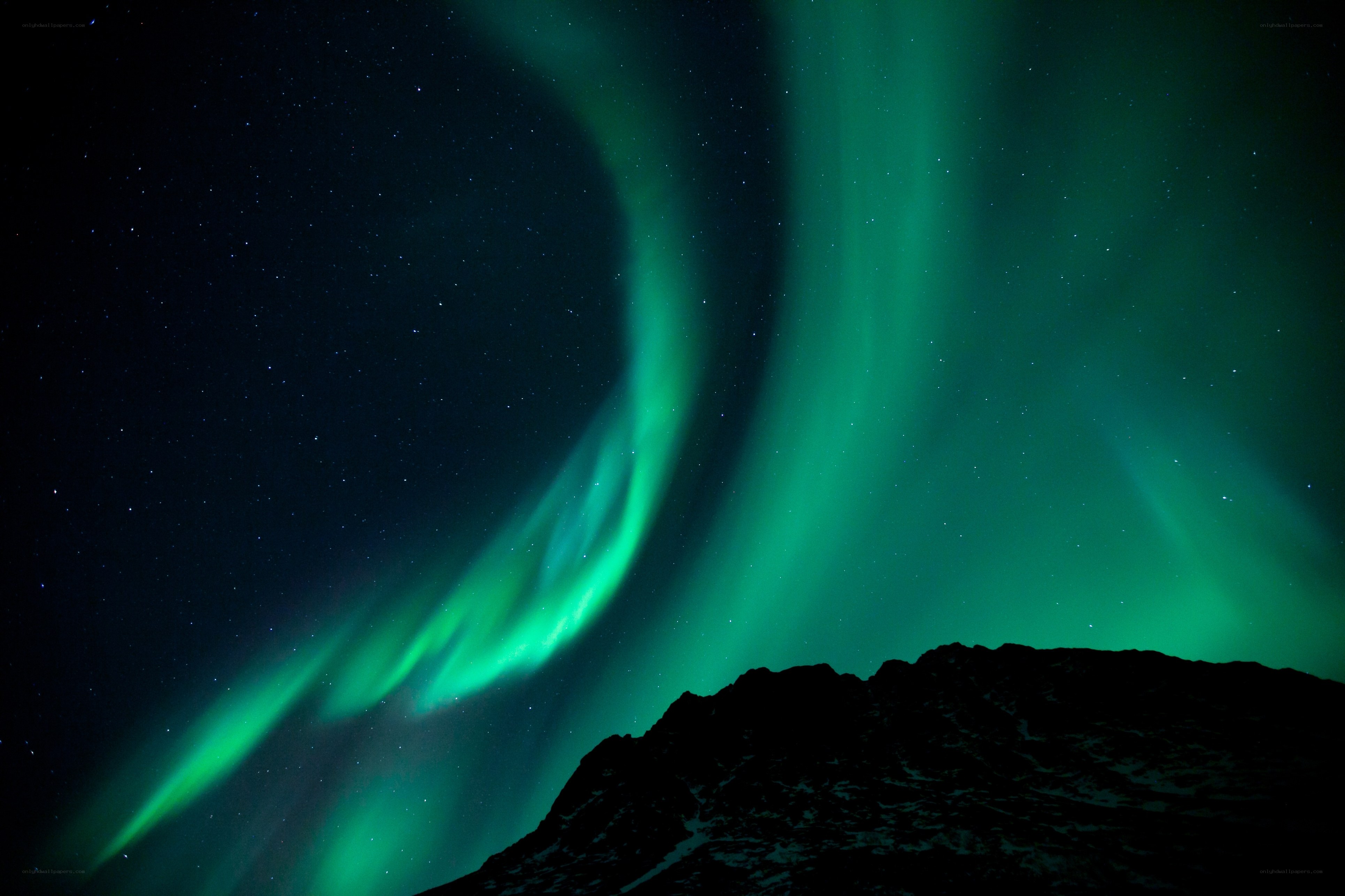 Green aurora over mountain silhouette