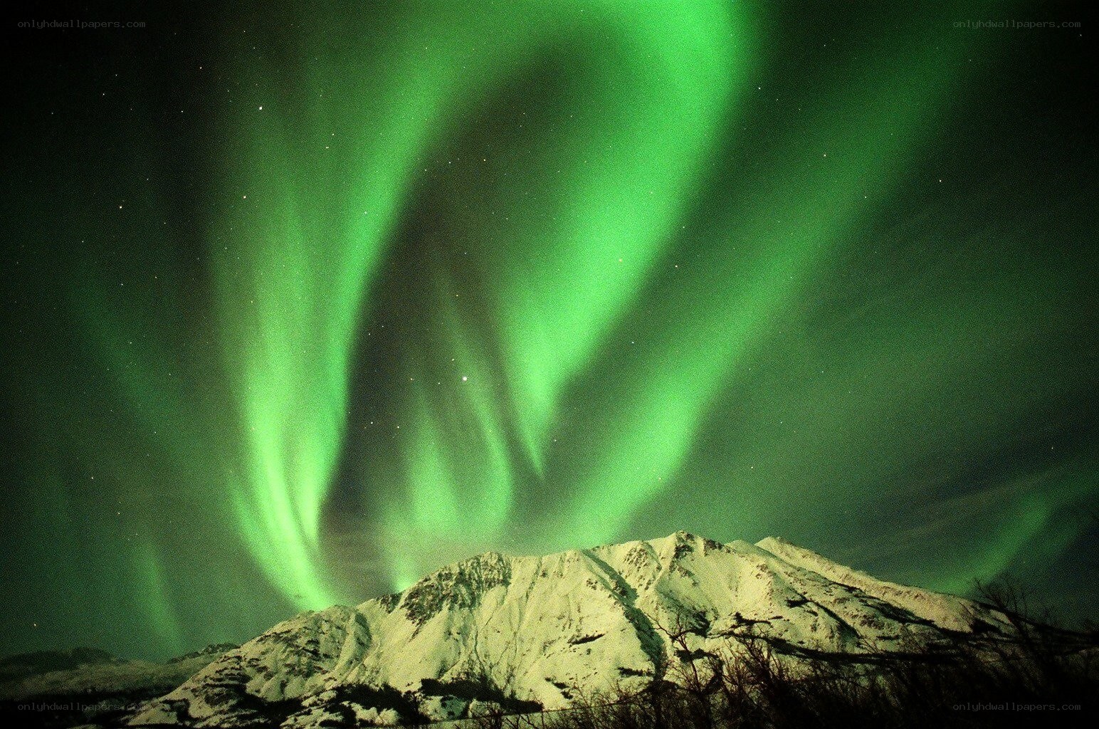 Green aurora over snowy mountains
