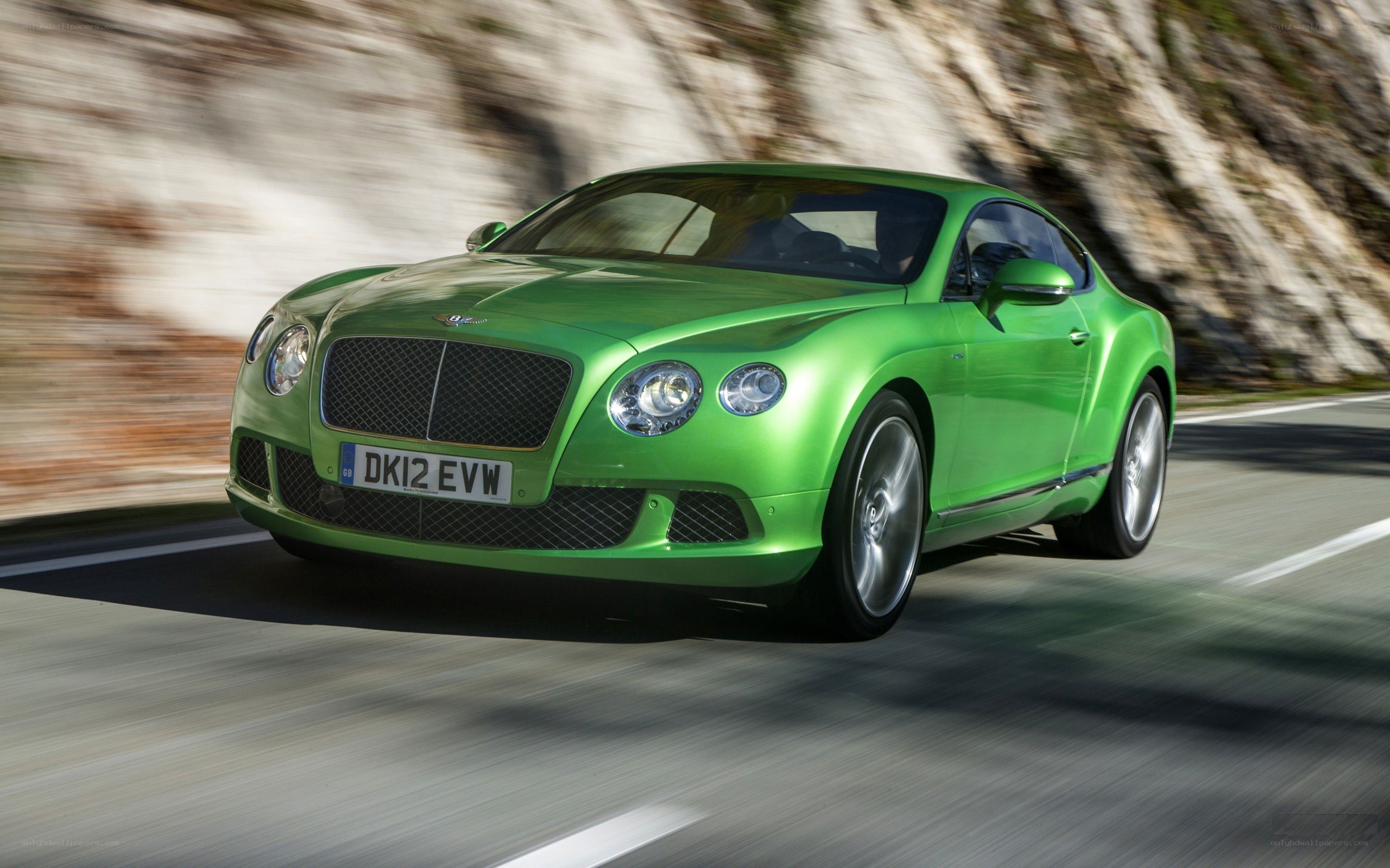 green bentley driving on road