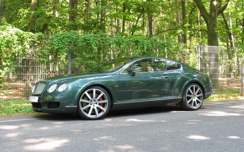 Green Bentley parked in forest