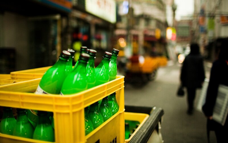 Green bottles in a yellow crate on street
