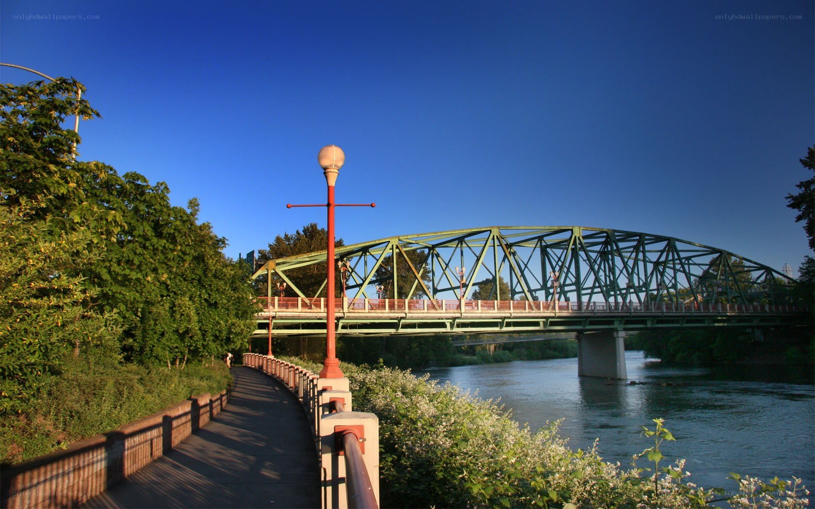 Green bridge over river at sunset