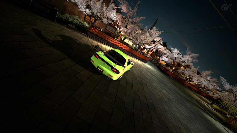 Green car at night under cherry blossoms