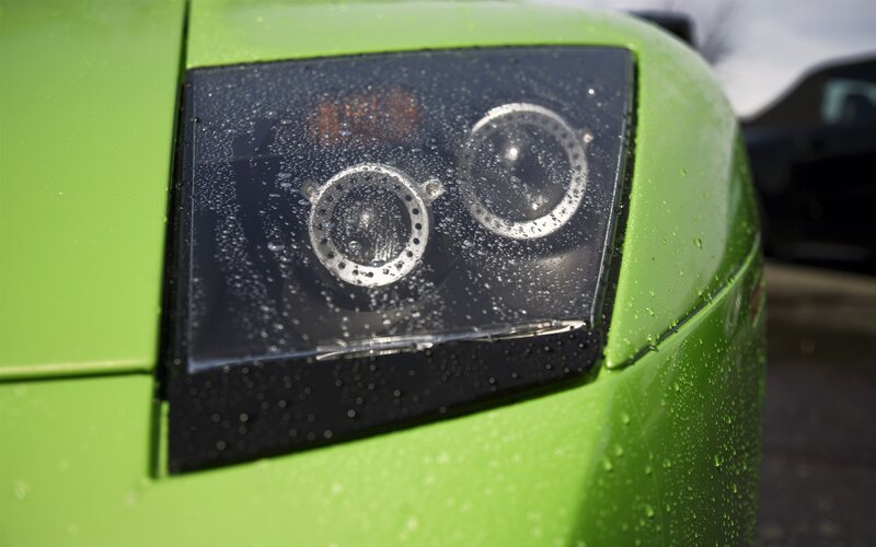 green car headlight with raindrops