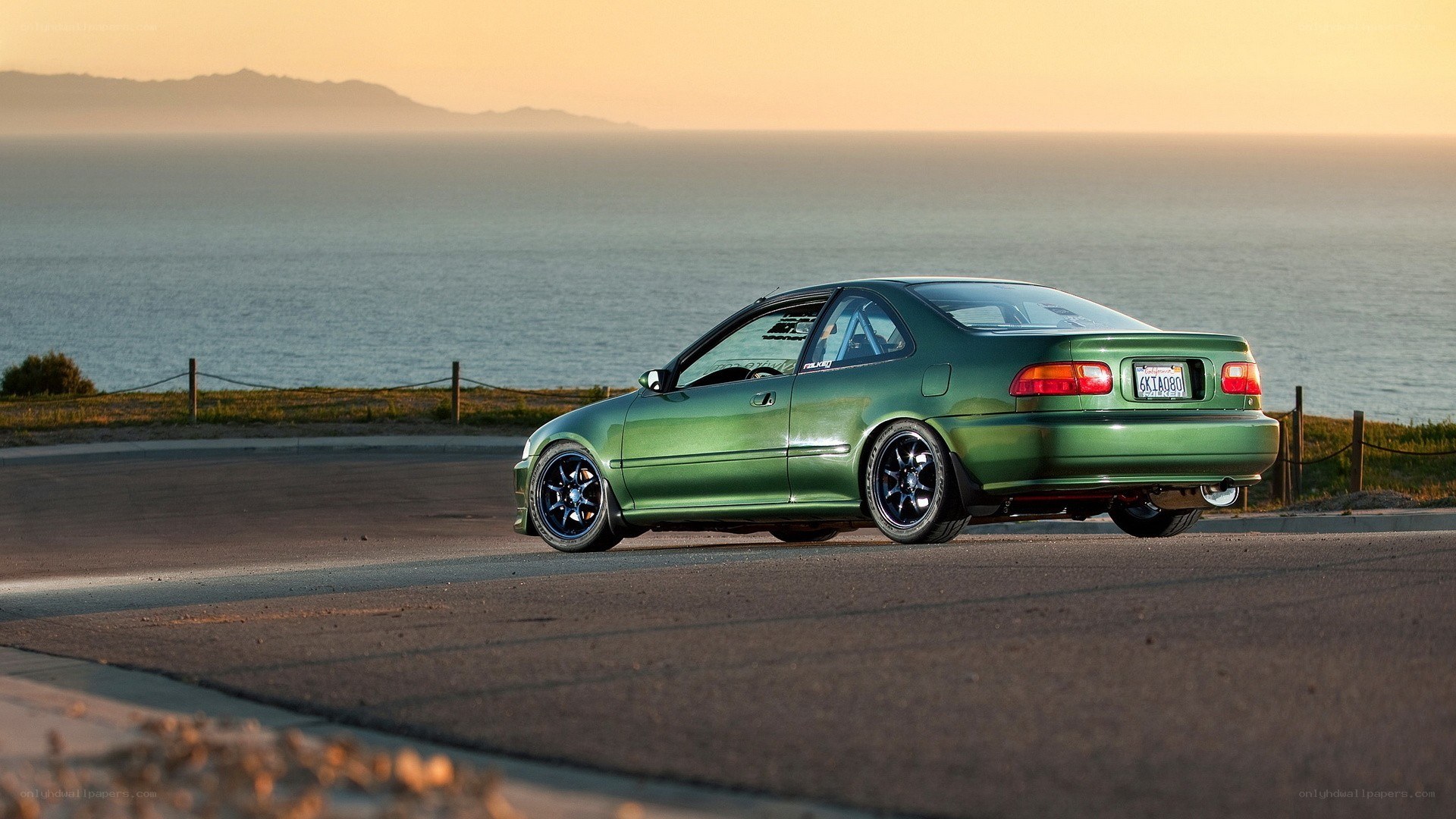 green car on coastal road