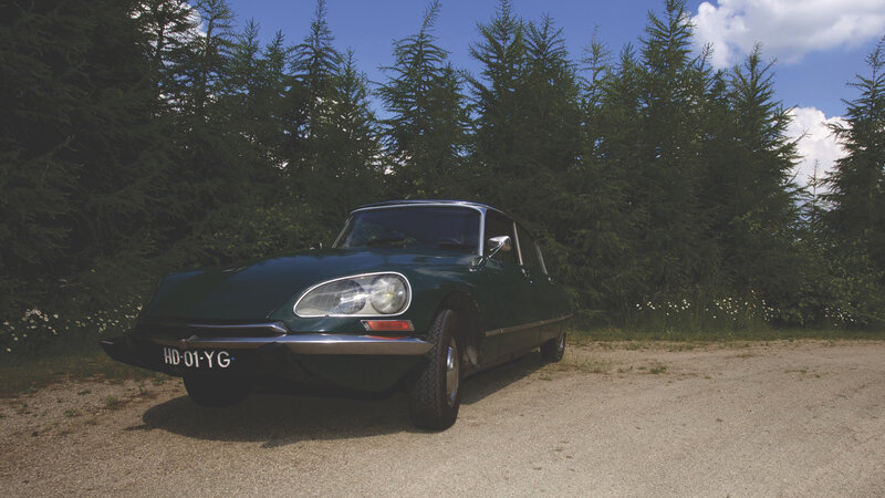 Green classic car in forest