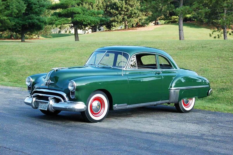 Green classic car on a driveway