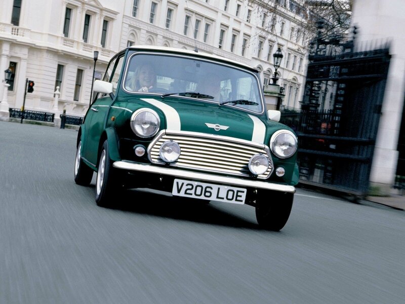 Green classic Mini driving in city