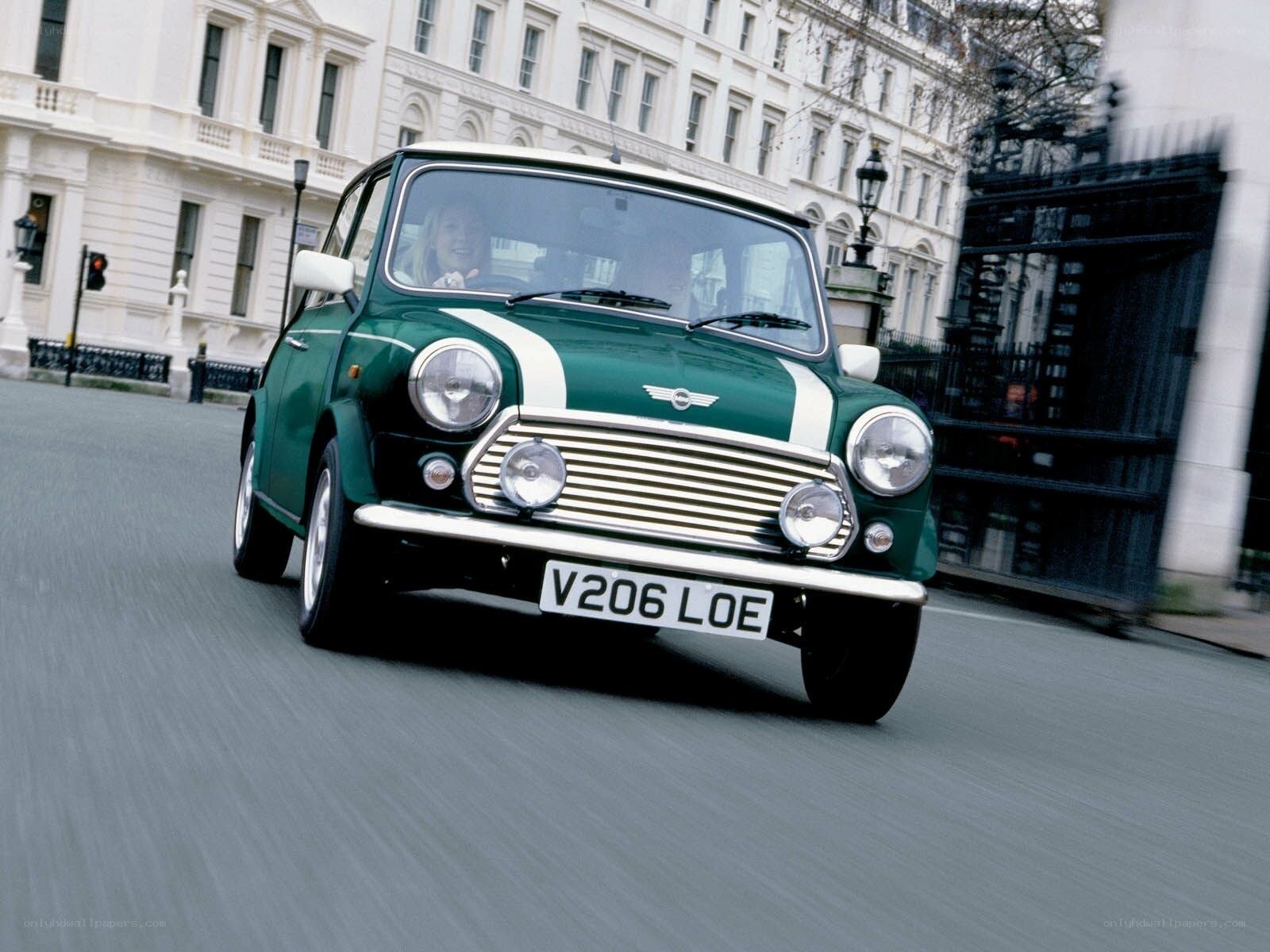 Green classic Mini driving in city