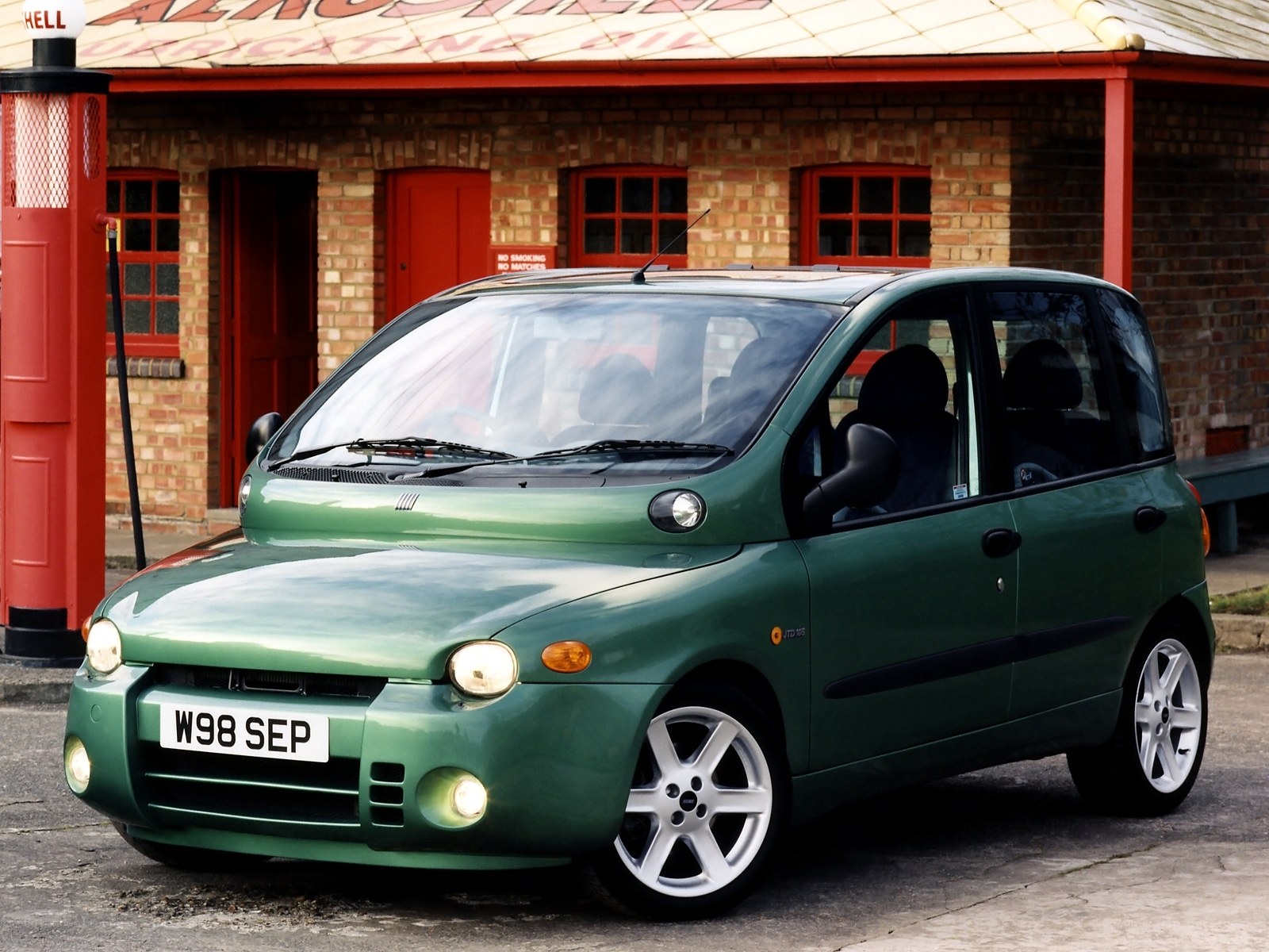 Green compact car at gas station