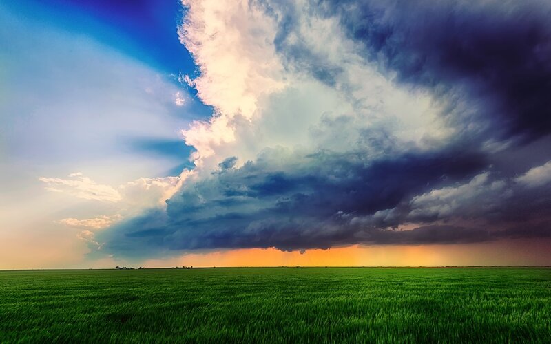 Green Field under Storm Clouds — Dramatic, Sunset