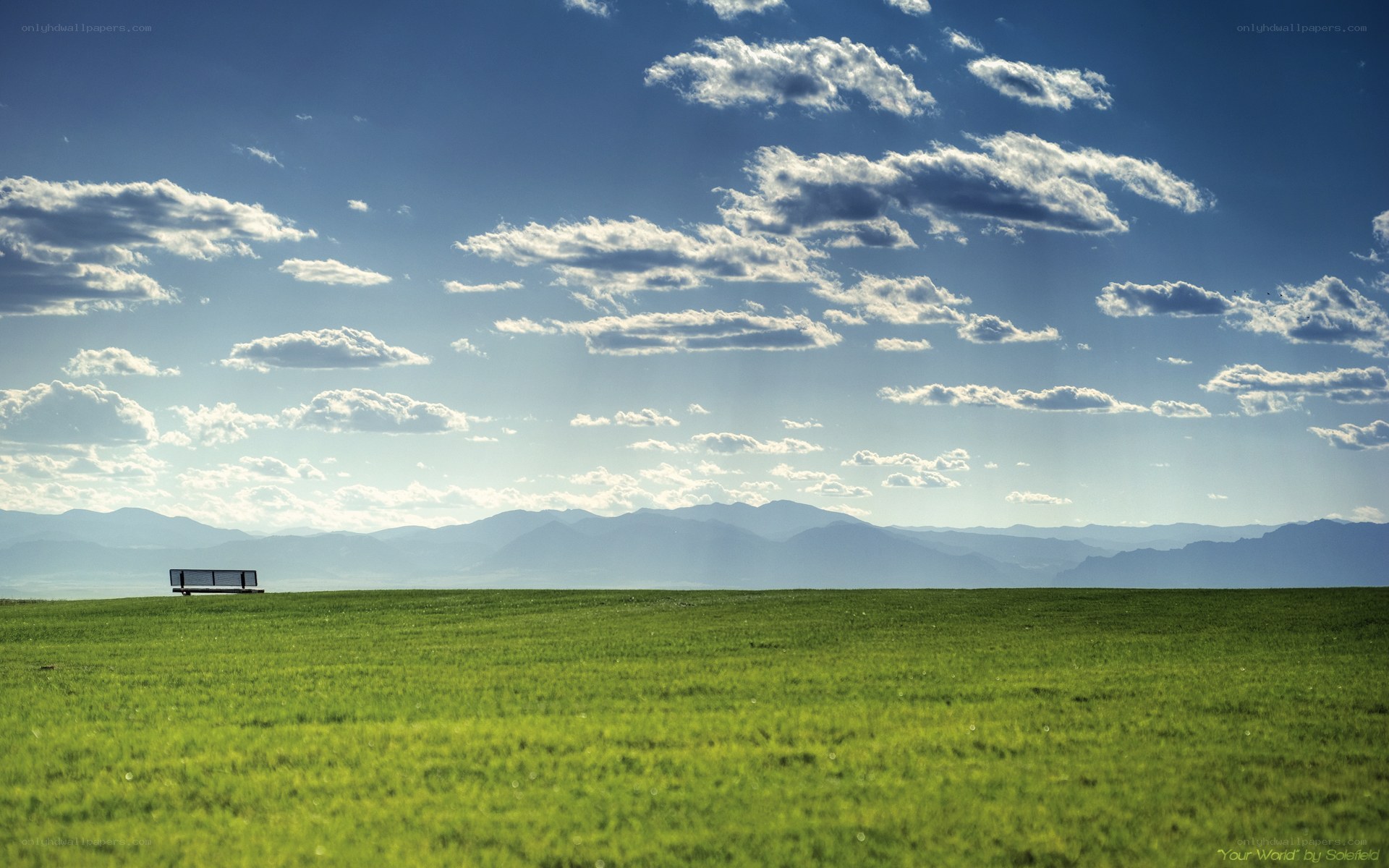 Green field with bench and mountains
