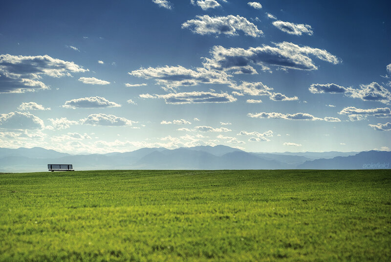 Green field with bench and mountains