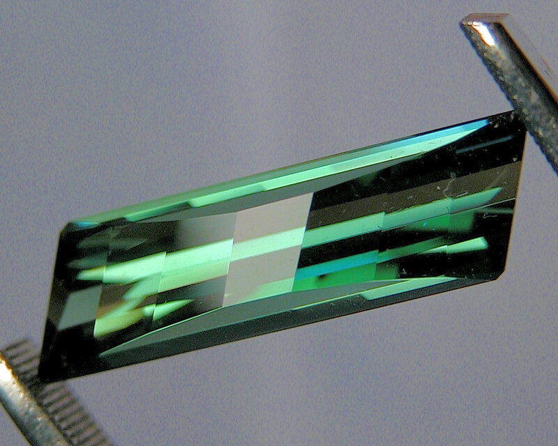 green gemstone in tweezers
